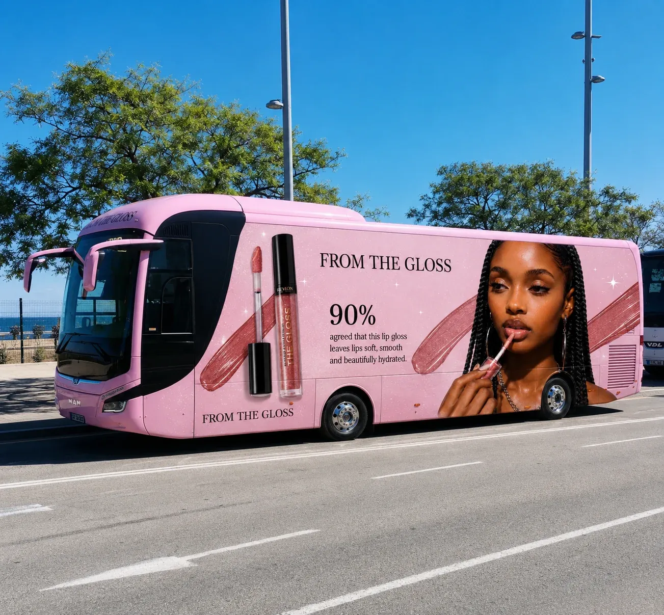 Mockup advert of a pink branded From The Gloss promotional bus parked at a beachside palm-lined road, featuring a Black model with long braids applying lip gloss on the side panel