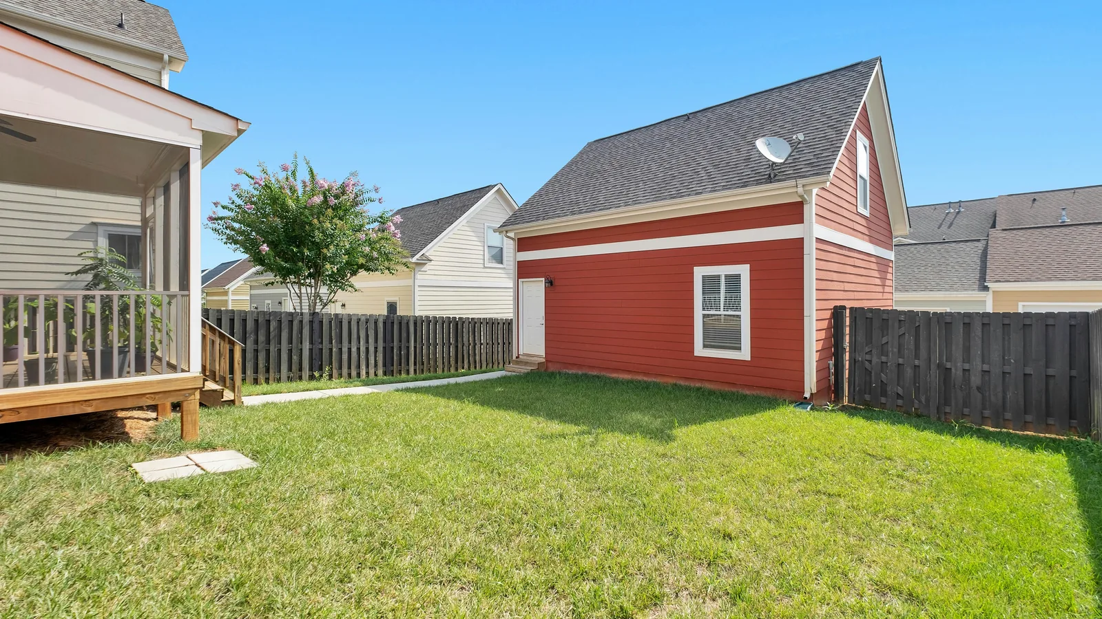 Before: a small bare-grass backyard with a red detached garage, a screened porch, and a paver path