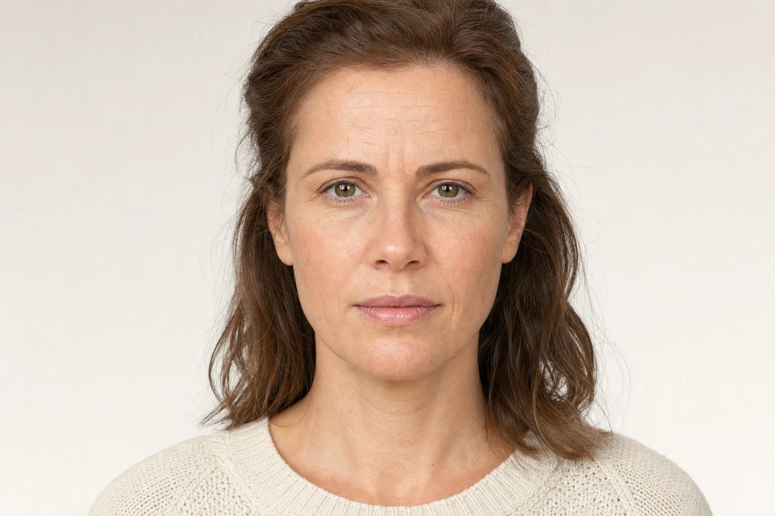 Synthetic patient before image: photorealistic clinical portrait of a woman in her late 30s with visible horizontal lines across her forehead and 11-lines at the glabella, neutral expression, natural shoulder-length warm brown hair, soft cream knit sweater, off-white studio backdrop, AI-generated illustration not based on any real person