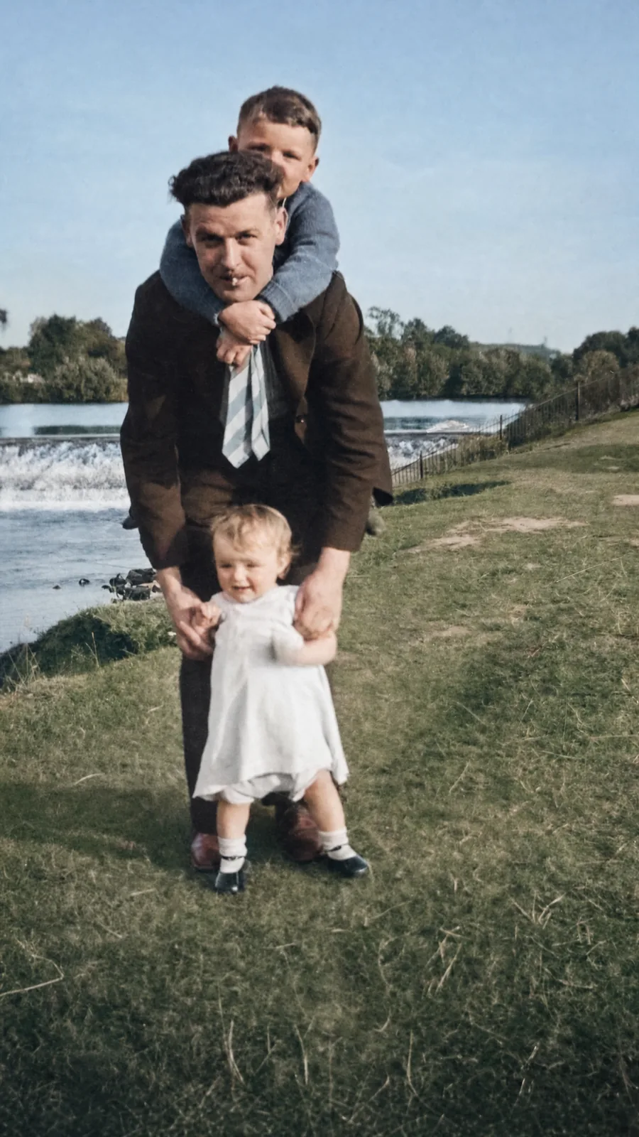 After: the same photo repaired and colorized, with the scratches gone, natural skin tones, a blue sky, and green grass, the faces unchanged