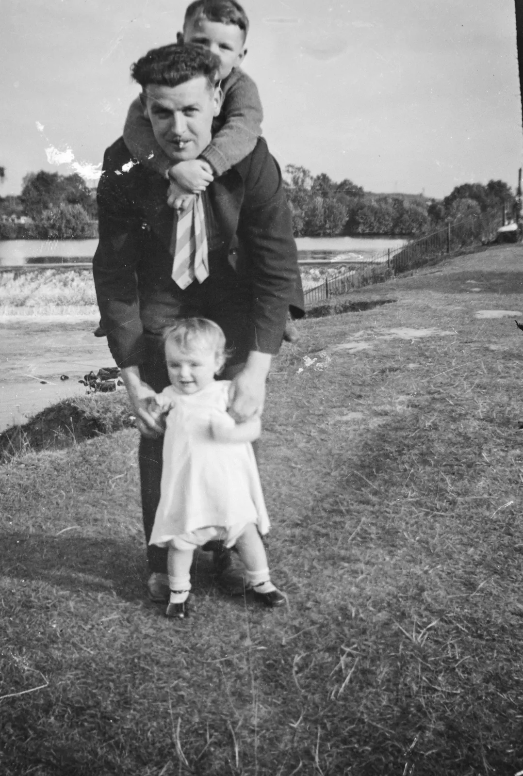 Before: a black-and-white photo of a father by a river holding a small girl's hands, with a boy on his shoulders, covered in scratches and surface marks