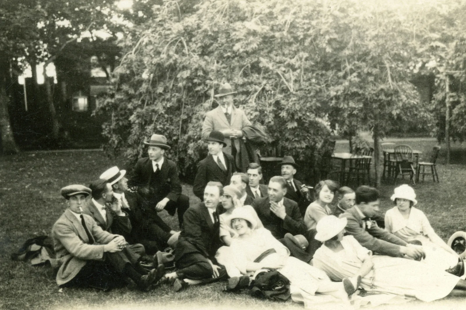 Before: a black-and-white family portrait of eleven people of different ages standing in a garden